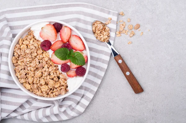 Müsli till frukost med bär och yoghrt på grå sten bakgrund. Hälsosam kost havregryn. Ovanifrån — Stockfoto