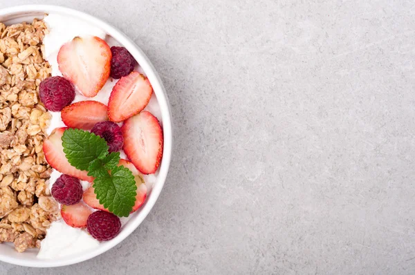 Müsli till frukost med bär och yoghurt på grå sten bakgrund. Hälsosam kost havregryn. Begreppet hälsosam livsstil och kost. Ovanifrån — Stockfoto