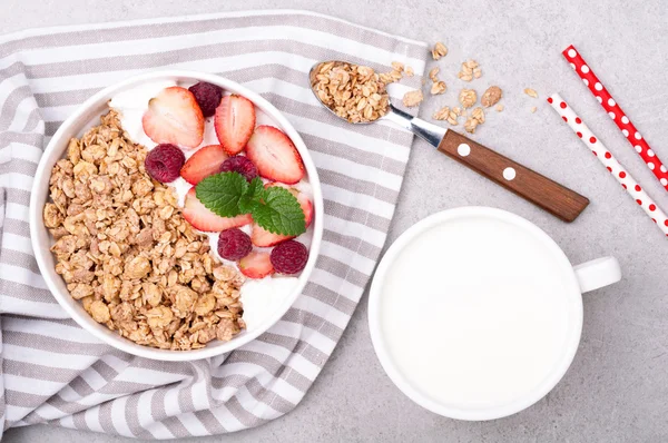 Müsli till frukost med bär, yoghurt och mjölk på grå sten bakgrund. Hälsosam kost havregryn. Begreppet hälsosam livsstil och kost — Stockfoto