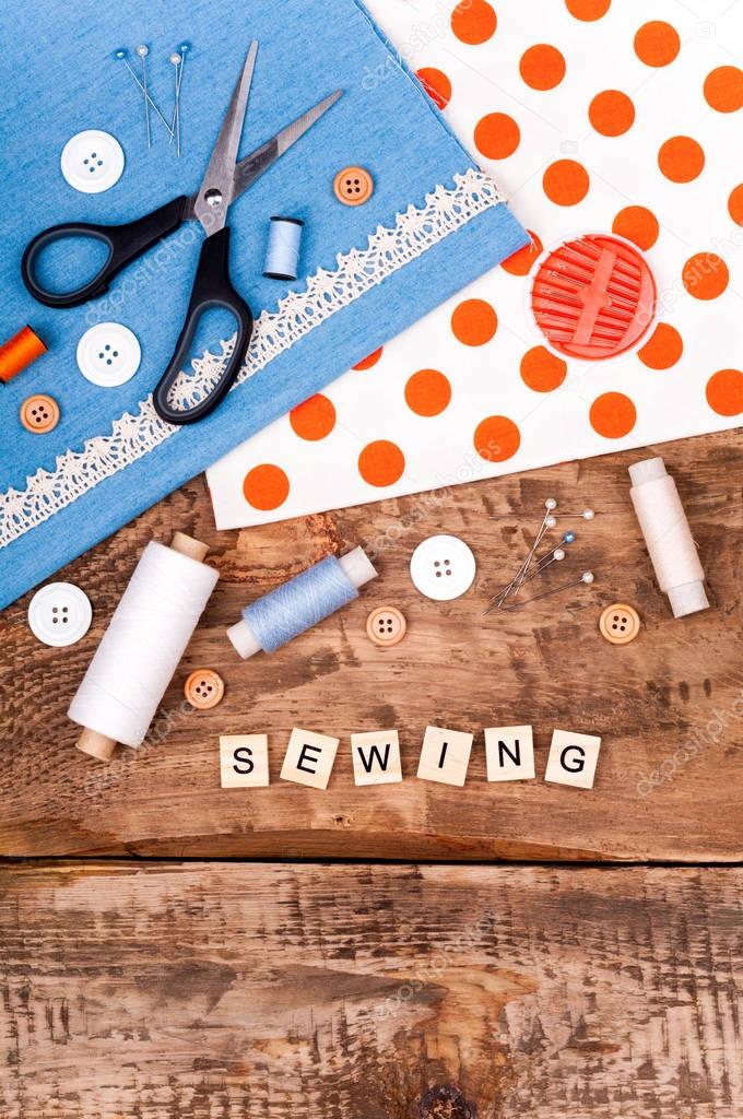 Sewing background. Fabric for sewing, lace and accessories for needlework on old wooden table. Spool of thread, scissors, buttons, sewing supplies. Set for needlework