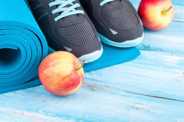 Équipement sportif et baskets. Tapis de yoga, chaussures de sport et pommes sur fond de bois bleu. Concept mode de vie sain, alimentation saine, sport et alimentation — Photo