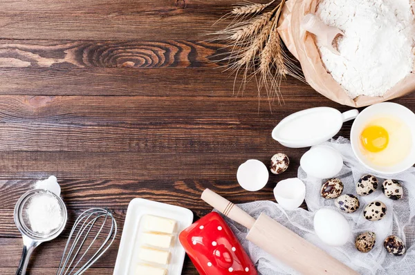 Ingredients for baking. Flour in paper bag, eggs, butter, kitchen utensils on wooden background. Cooking bread, cake or cookies. Copy space — Stock Photo, Image