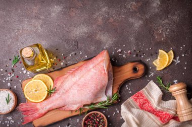 Limon dilimleri, otlar biberiye, tuz ve biber rustik taş zemin üzerine taze çiğ balığı balık süslenmiş. Sağlıklı gıda ve beslenme kavramı. Balık Pişirme için malzemeler