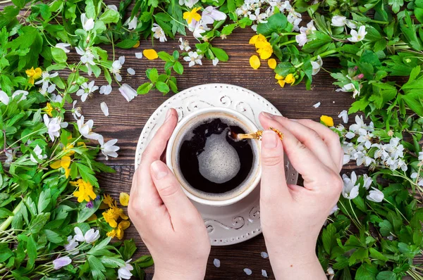 Mani femminili che tengono la tazza di caffè. Primavera. Fiori e caffè su sfondo rustico in legno — Foto Stock