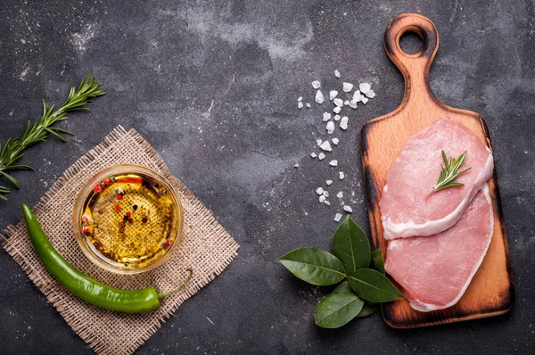 Carne crua no fundo escuro. Bife cru de porco com ervas, óleo e especiarias. Cozinhar carne. Espaço de cópia — Fotografia de Stock