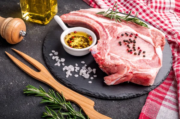 Syrové maso na tmavém pozadí. Surový Vepřový steak s bylinkami, oleje a koření. Vaření masa — Stock fotografie