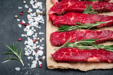 Koyu arka plan üzerinde çiğ et. Ham sığır straganof otlar ve baharatlar ile kapatın. Et pişirme