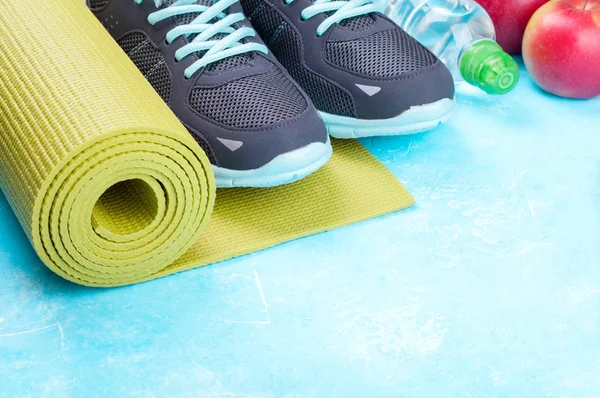 Esterilla de yoga, zapatos deportivos, manzanas, botella de agua sobre fondo azul. Concepto de estilo de vida saludable, comida saludable, deporte y dieta. Equipamiento deportivo — Foto de Stock