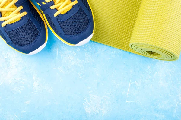 Tapis de yoga et chaussures de sport sur fond bleu. Concept mode de vie sain, sport et alimentation. Equipements sportifs — Photo