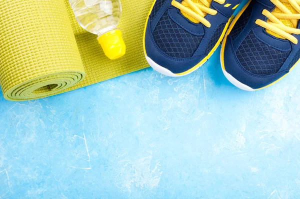 Tapis de yoga, chaussures de sport et bouteille d'eau sur fond bleu. Concept mode de vie sain, sport et alimentation. Equipements sportifs — Photo