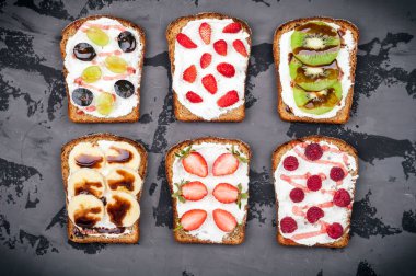 Sağlıklı kahvaltı. Krem peynir ve taze meyveler ve meyve koyu arka plan üzerinde tatlı sandviç. Kahvaltı için tost
