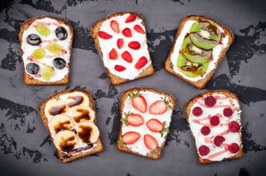 Sağlıklı kahvaltı tost ile. Krem peynir ve taze meyveler ve meyve koyu arka plan üzerinde tatlı sandviç. Sağlıklı beslenme ve diyet kavramı