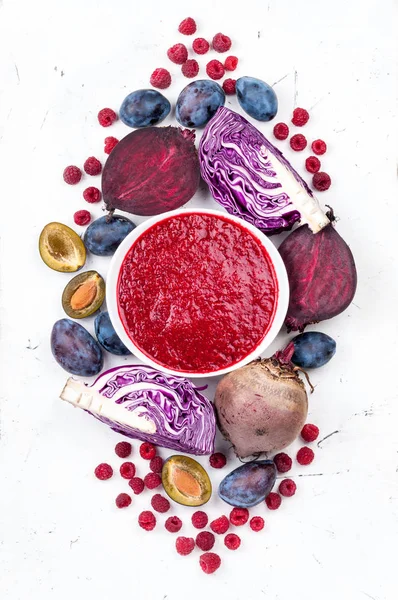 Smoothies bowl with purple fruit and vegetables on white background. Healthy eating and diet concept