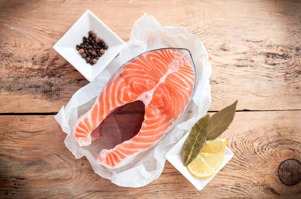 Стейк из сырой лосося с лимоном и специями на деревянном деревенском фоне. Свежая рыба — стоковое фото