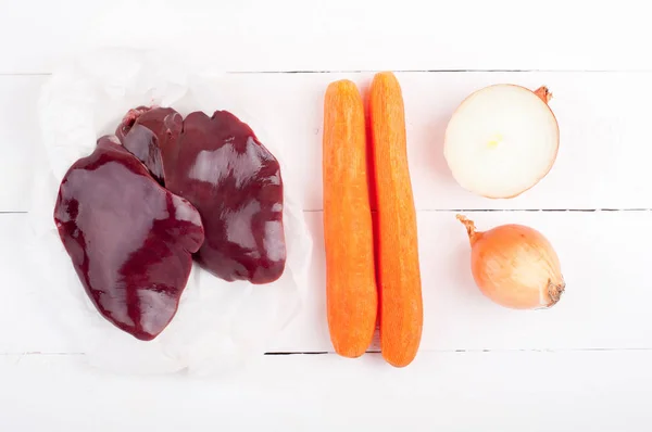 Rauwe lever en groenten wortelen en UI op witte houten achtergrond. Ingrediënten voor het koken lever of pate — Stockfoto