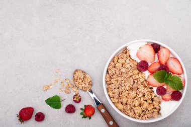 Sağlıklı kahvaltı granola, çilek ve gri arka plan üzerine yoğurt. Yulaf ezmesi yeme sağlıklı. Üstten Görünüm