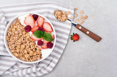 Sağlıklı kahvaltı granola, çilek ve gri arka plan üzerine yoğurt. Yulaf ezmesi yeme sağlıklı. Üstten Görünüm