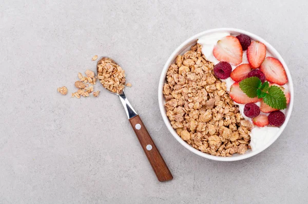 Hälsosam frukost med granola, bär och yoghurt på grå bakgrund. Hälsosam kost havregryn. Ovanifrån — Stockfoto
