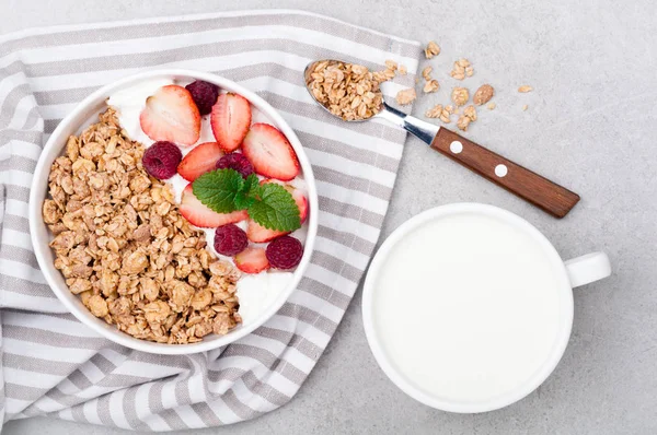 Frukost med granola, bär, yoghurt och mjölk på grå sten bakgrund. Hälsosam kost havregryn. Begreppet hälsosam livsstil och kost — Stockfoto