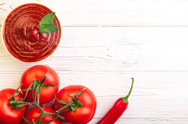 Tomaten ketchup saus in een kom met chili, basilic en tomaten. Ingrediënten voor het koken van ketchup — Stockfoto