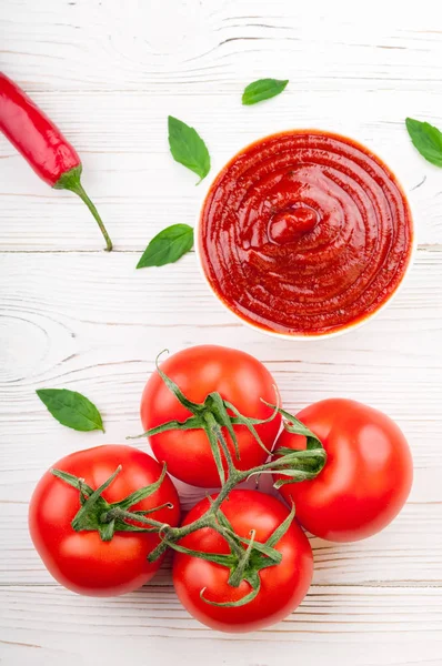 Salsa al ketchup di pomodoro in una ciotola con peperoncino, basilico e pomodori. Ingredienti per cucinare il ketchup — Foto Stock