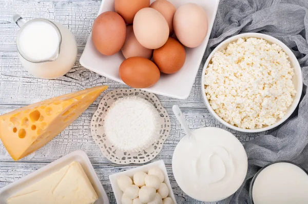 Mejeriprodukter på träbord. Mjölk, gräddfil, ost, ägg, yoghurt och smör. Hälsosam mat, kost koncept — Stockfoto