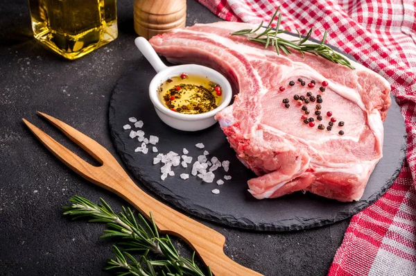 Carne cruda con hierbas, aceite y especias sobre fondo oscuro. Carne de cerdo cruda —  Fotos de Stock