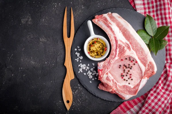 Carne cruda con hierbas, aceite y especias sobre fondo oscuro. Filete de cerdo crudo. Ingredientes para cocinar carne —  Fotos de Stock