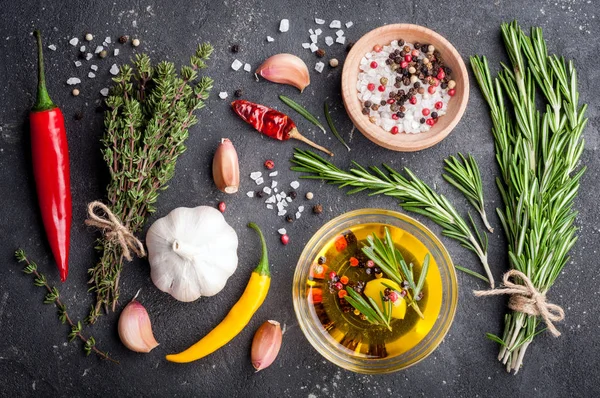 Erbe e spezie. Rosmarino, timo, peperoncino, aglio, olio d'oliva, sale e pepe sul tavolo scuro. Ingredienti di cottura — Foto Stock