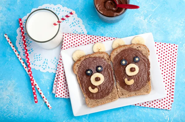 Kinderfrühstück mit Sandwiches und Milch. Lustige Bärengesicht-Sandwiches mit Schokoladenpaste, Banane, Nüssen und Beeren — Stockfoto