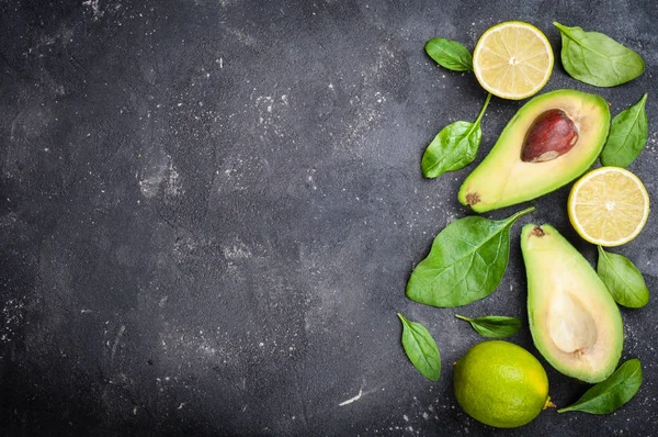 Avocado con foglie di spinaci e tiglio su sfondo di cemento scuro — Foto Stock