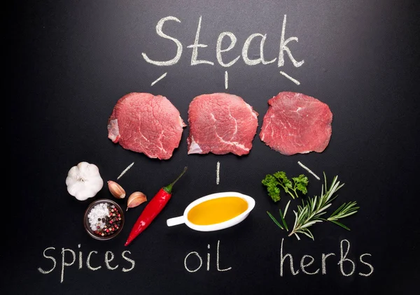 生肉。生牛肉牛排迷迭香与香料的黑板上 — 图库照片