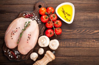 Tavuk ızgara için baharatlar, bitkiler, zeytin yağı, domates, mantar koyu arka plan, üstten görünüm üzerinde. Çiğ et tavuk yemek pişirmek için