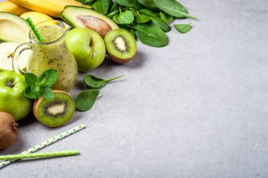 Kivi, avokado, muz, elma ve ıspanak ile sağlıklı Detoks güler yüzlü. Gri zemin üzerine yeşil smoothie. Sağlıklı gıda ve beslenme kavramı