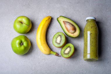 Sağlıklı yeşil smoothie ve malzemelerin gri arka plan üzerine. Kivi smoothie meyve ile. Superfoods, diyet, Detoks, sağlık, vejetaryen yemek