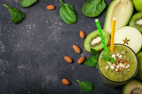 Smoothie verde saludable e ingredientes sobre fondo oscuro. Batido kiwi con frutas y almendras. Superalimentos, dieta, desintoxicación, salud, comida vegetariana — Foto de Stock