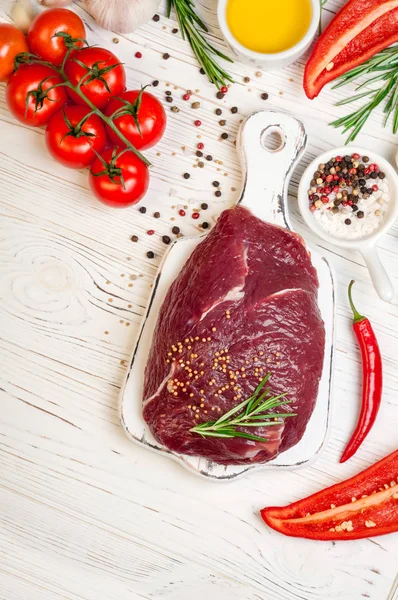 Carne cruda con hierbas, especias y condimentos sobre fondo de madera blanca, ingredientes para cocinar, vista superior. Carne de res en la tabla de cortar —  Fotos de Stock