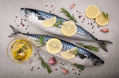 Taze balık. Tuz, limon ve baharat gri arka plan üzerinde ham uskumru. Otlar ile Balık Pişirme