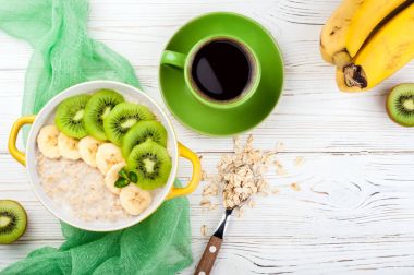 Yulaf lapası, kahve ve meyve kahvaltı. Kivi ve muz yulaf ezmesi. Sağlıklı kahvaltı ve kavram yeme. Üstten Görünüm