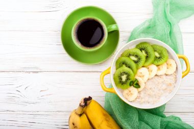 Yulaf lapası, kahve ve meyve kahvaltı. Kivi ve muz yulaf ezmesi. Sağlıklı kahvaltı ve kavram yeme. Üstten Görünüm