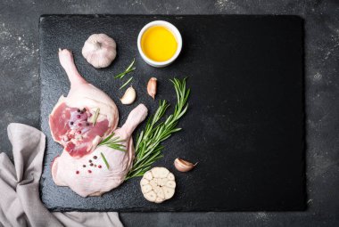 Çiğ kanatlı eti. Biberiye, baharat ve zeytinyağı koyu arka plan üzerinde kesme tahtası üzerinde ördek ayaklı