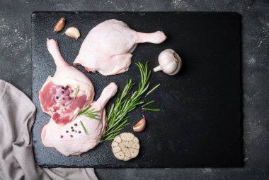 Çiğ kanatlı eti. Biberiye, baharatlar ve zeytinyağı koyu arka plan üzerinde kesme tahtası üzerinde ördek bacaklar. Et yemek pişirmek için malzemeler