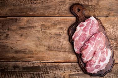 Kesme tahtası üstten görünüm üzerinde domuz biftek. Çiğ et