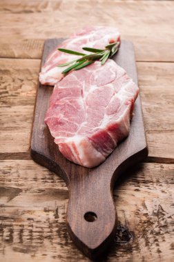 Çiğ et. Otlar ve baharatlar rustik ahşap arka plan üzerinde kesme tahtası üzerinde domuz eti biftek