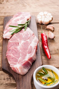 Çiğ et. Domuz eti biftek otlar ve baharatlar üzerinde kesme tahtası INGR