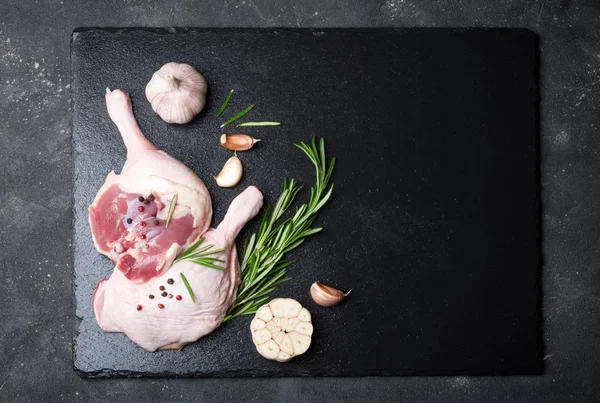 Çiğ et, biberiye, zeytin yağı ve baharatlar ile siyah arka plan üzerinde ördek bacaklar
