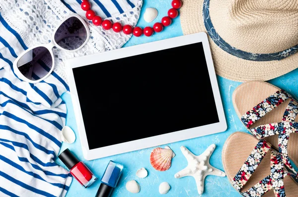 Accesorios para mujer de verano: gafas de sol, sombrero, sandalias, camisa y tablet sobre fondo azul. Concepto de vacaciones, viajes y trabajo freelance — Foto de Stock