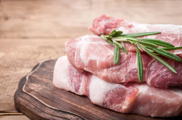 Carne crua com ervas. Bife de porco com alecrim na tábua de corte — Fotografia de Stock