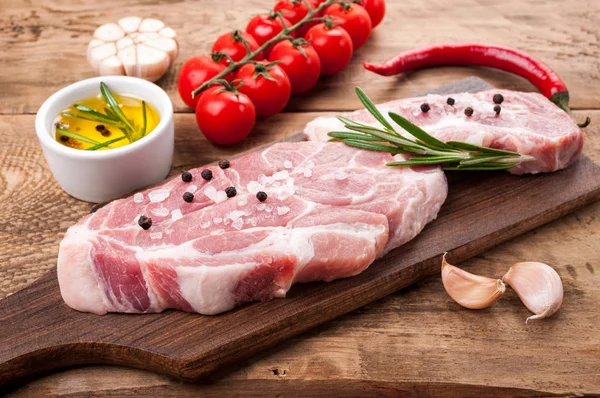 生肉。猪肉牛排配香草香料和蔬菜在砧板上 — 图库照片