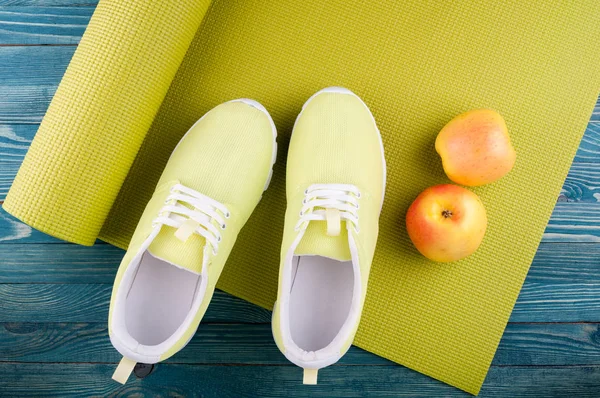 Fond sportif. Tapis de yoga, chaussures de sport, pommes fruits sur fond en bois. Mode de vie sain, régime alimentaire, yoga, concept sportif — Photo